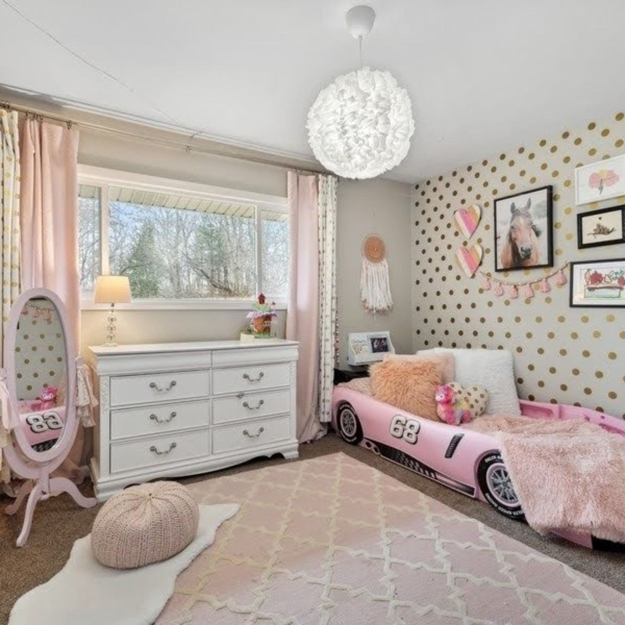 A vibrant pink and gold themed staged girls bedroom featuring a stylish car bed as the centerpiece.