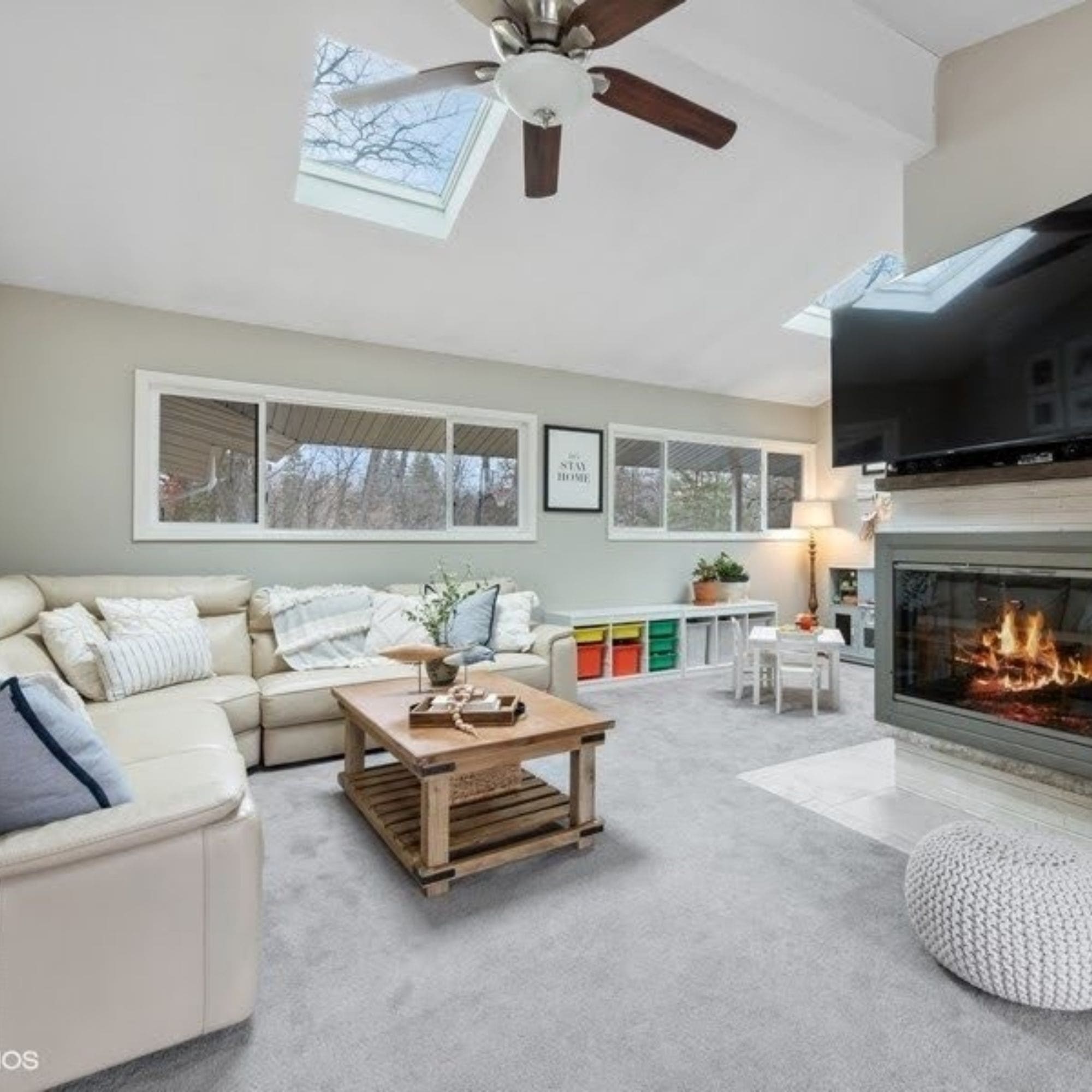 A well-equipped home staged living room with a fireplace, TV, and ceiling fan.