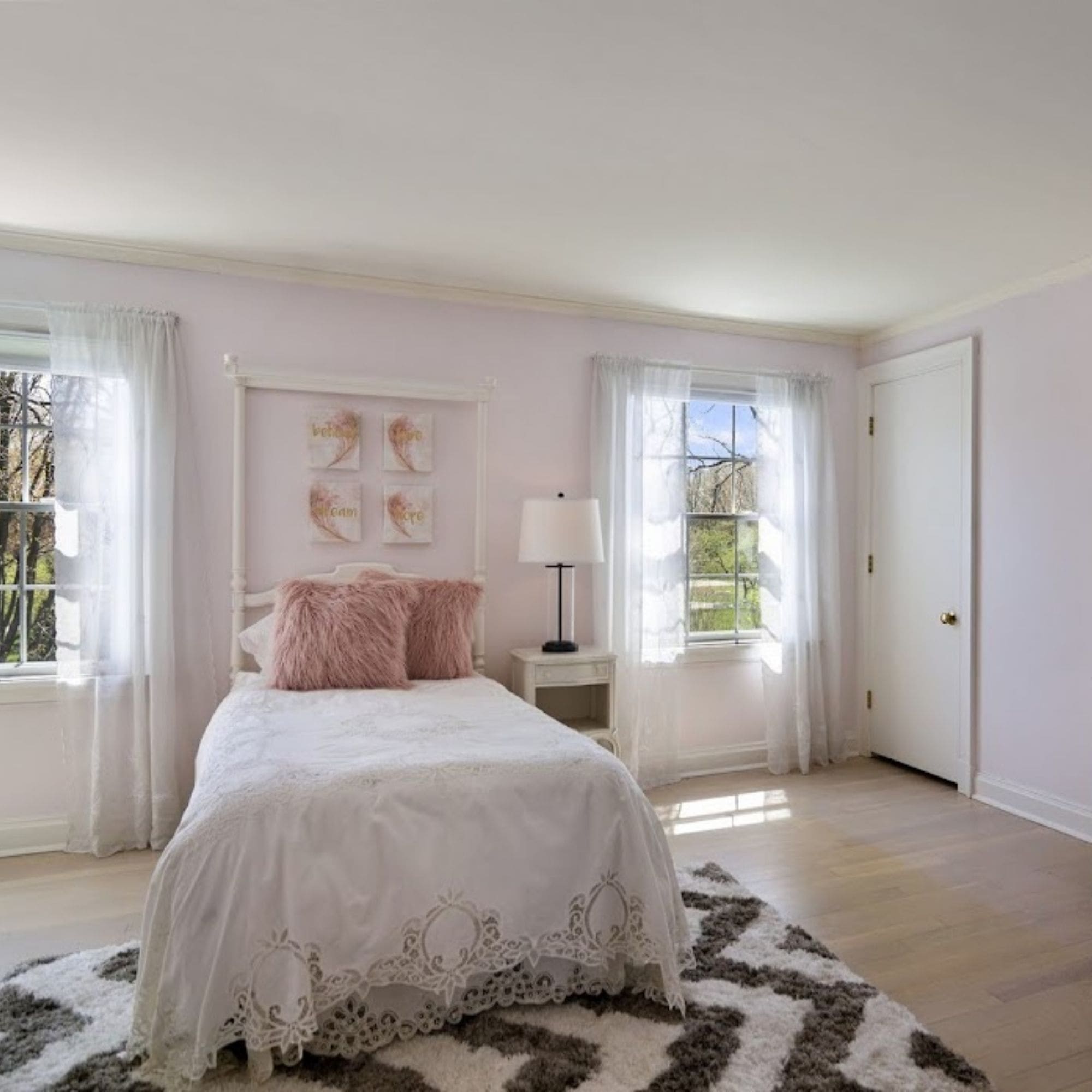 A stylish home staged bedroom showcasing a pink bed against a backdrop of clean white walls.