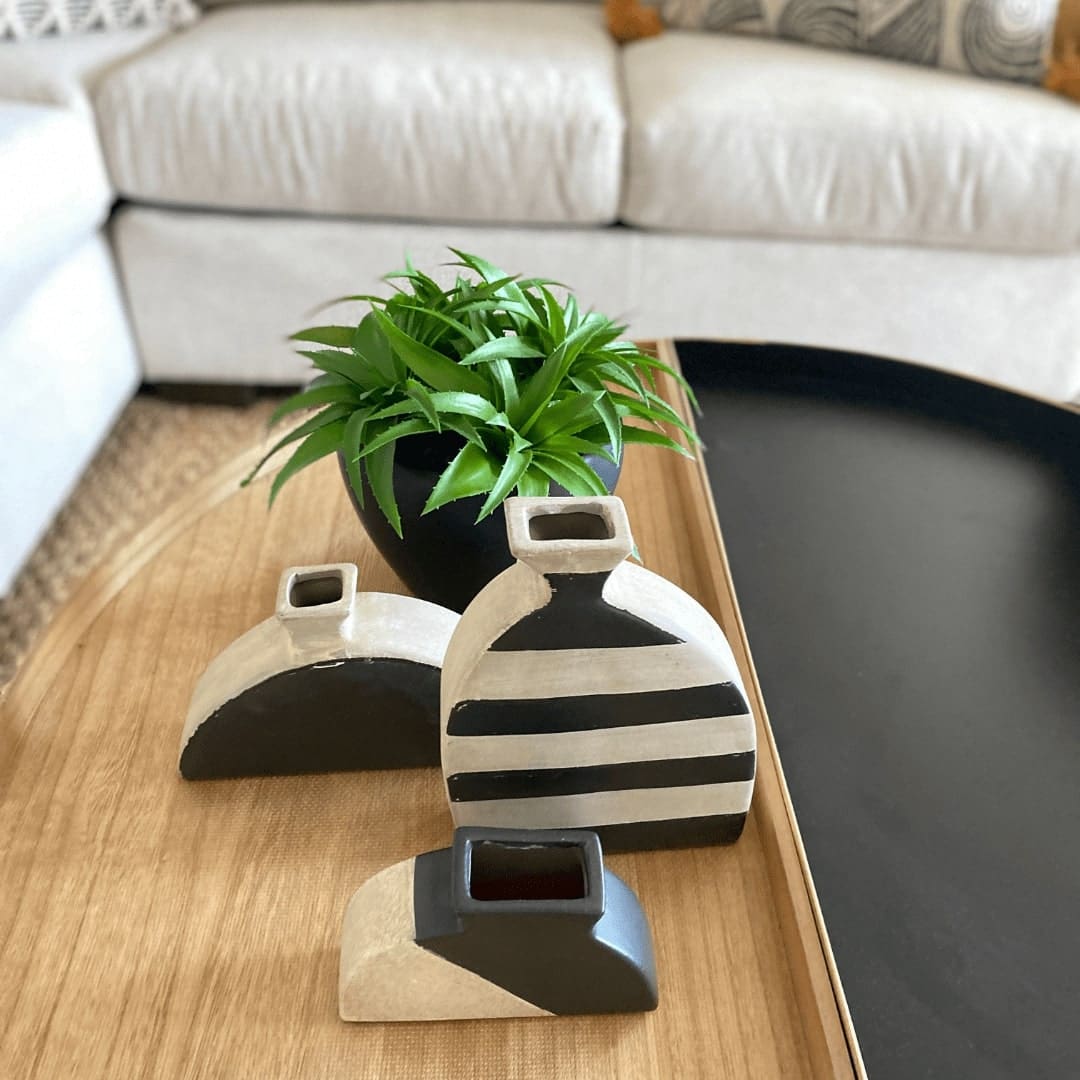 A coffee table adorned with three vases, featuring a black and white color scheme.