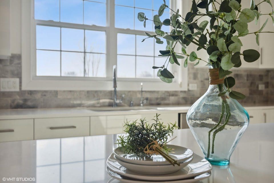 A vase filled with green plants sits on a countertop, adding a touch of nature to the room.