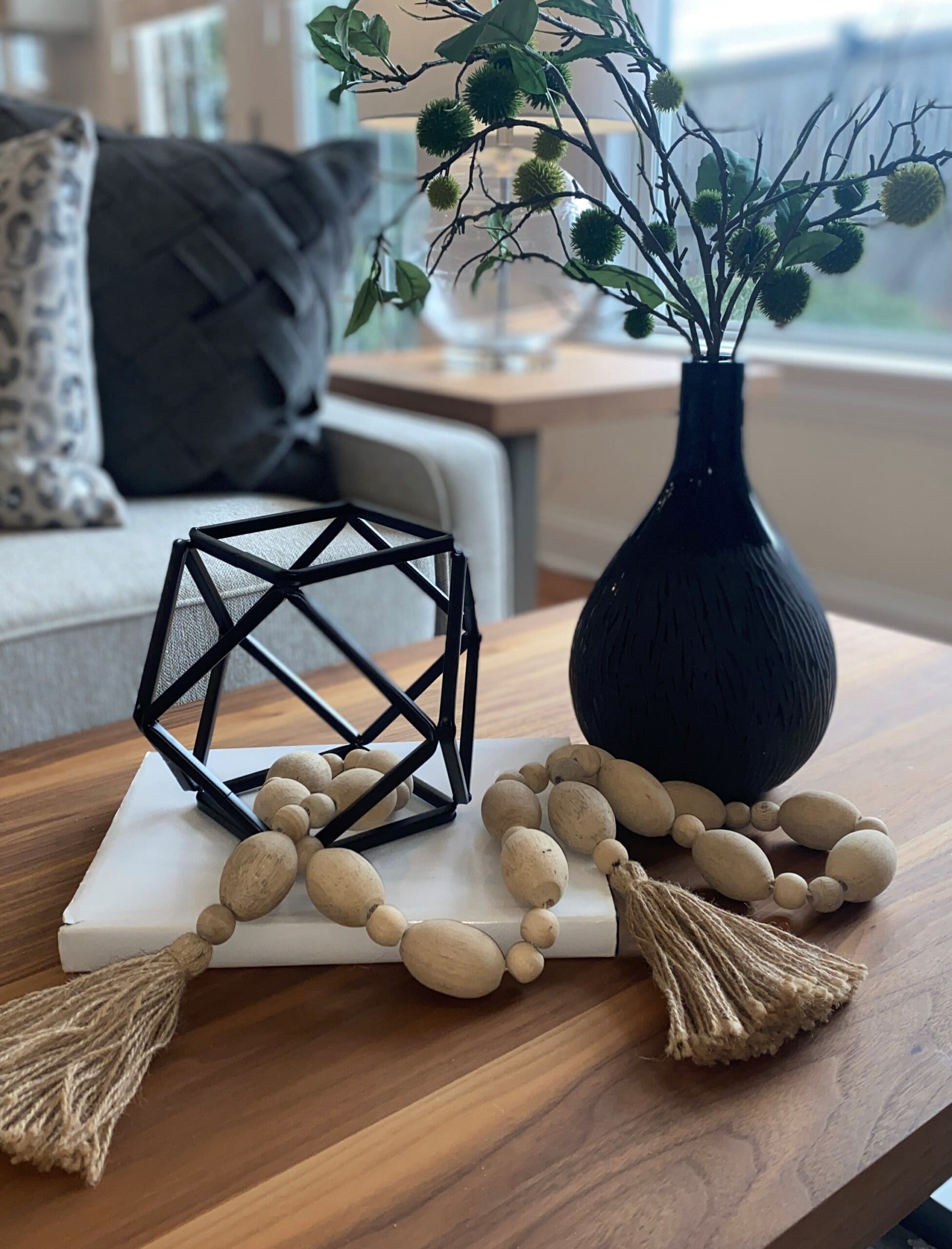 A wooden coffee table adorned with a vase and a black and white geometric sculpture.