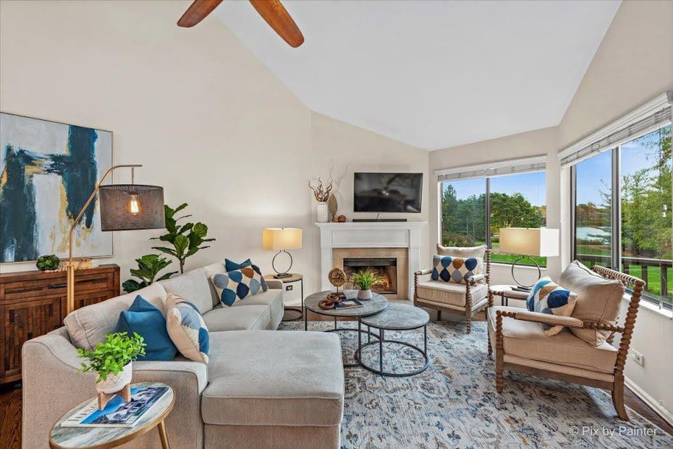 A well-furnished staged living room with a fireplace, plush couches, and a ceiling fan for added comfort.